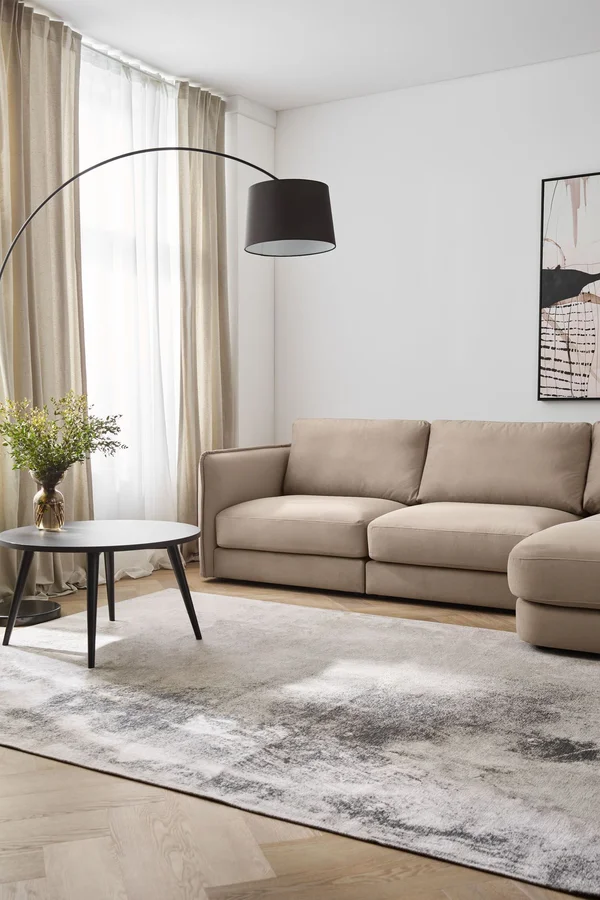 Beżowa sofa z łukową lampą i abstrakcyjnym obrazem w salonie